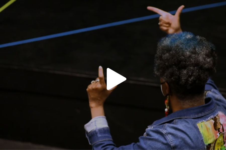 Click here: A still frame with a play button of a behind the scenes video